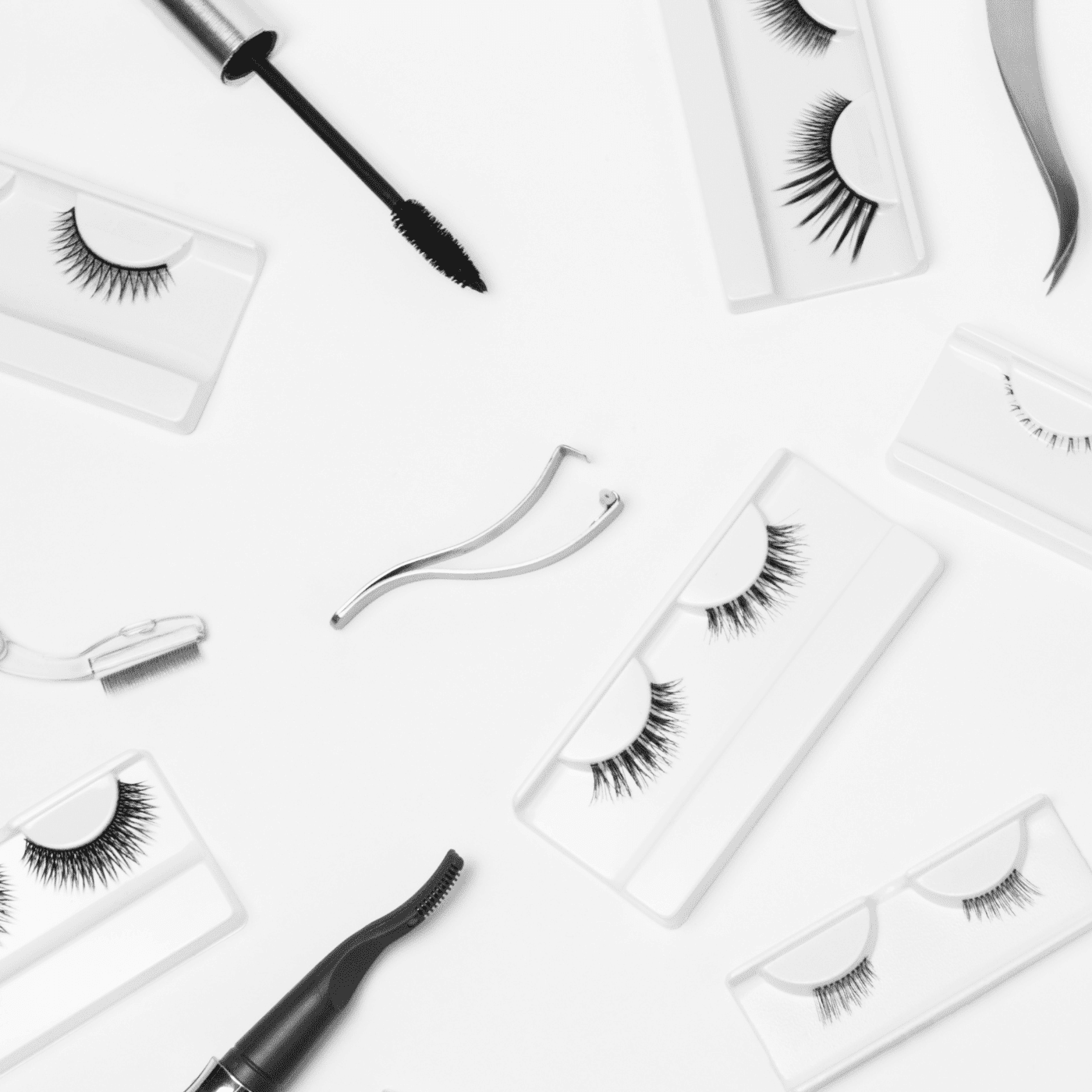 False eyelashes, mascara, and applicators arranged on a white background.
